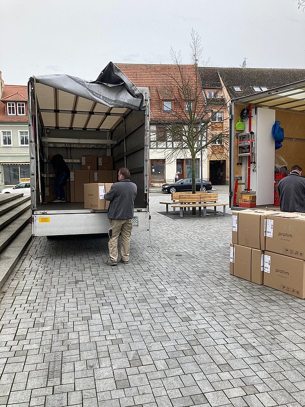 Rückansicht eines LWK mit geöffneter Plane beim Ausladen diverser Kartons während des Umbaus der Präsenzstelle