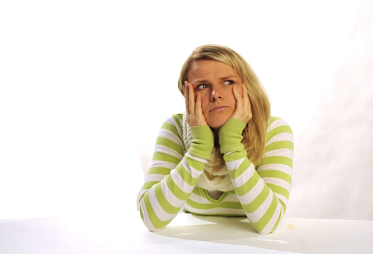 Junge Frau, das Gesicht auf die Hände gestützt.